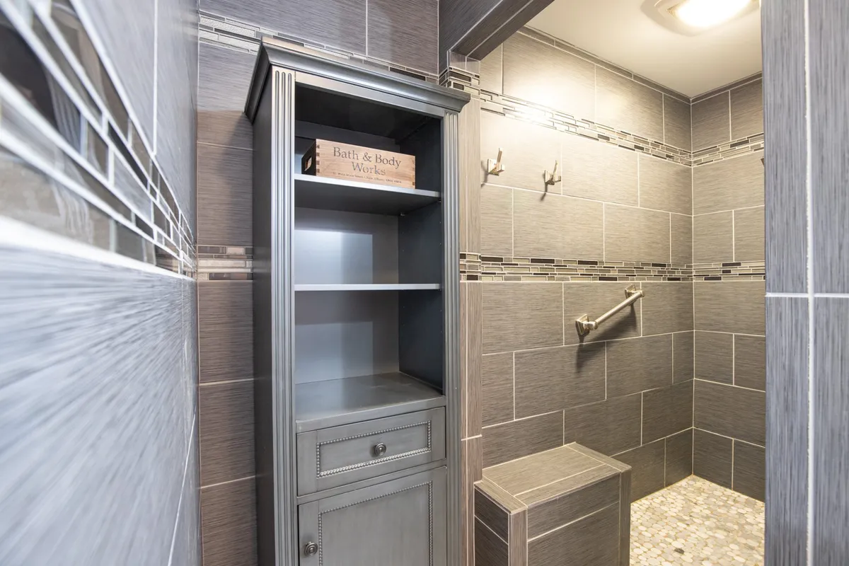 A spa-like bathroom featuring a modern shower area, clean tile design, and a practical storage cabinet. The organized layout and calming decor evoke a sense of relaxation and privacy.