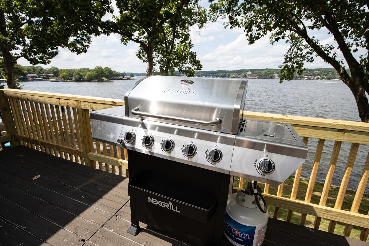 A sunny deck scene with a grill overlooking the water, perfect for barbecuing, socializing, and relaxing as the sun sets over the lake.