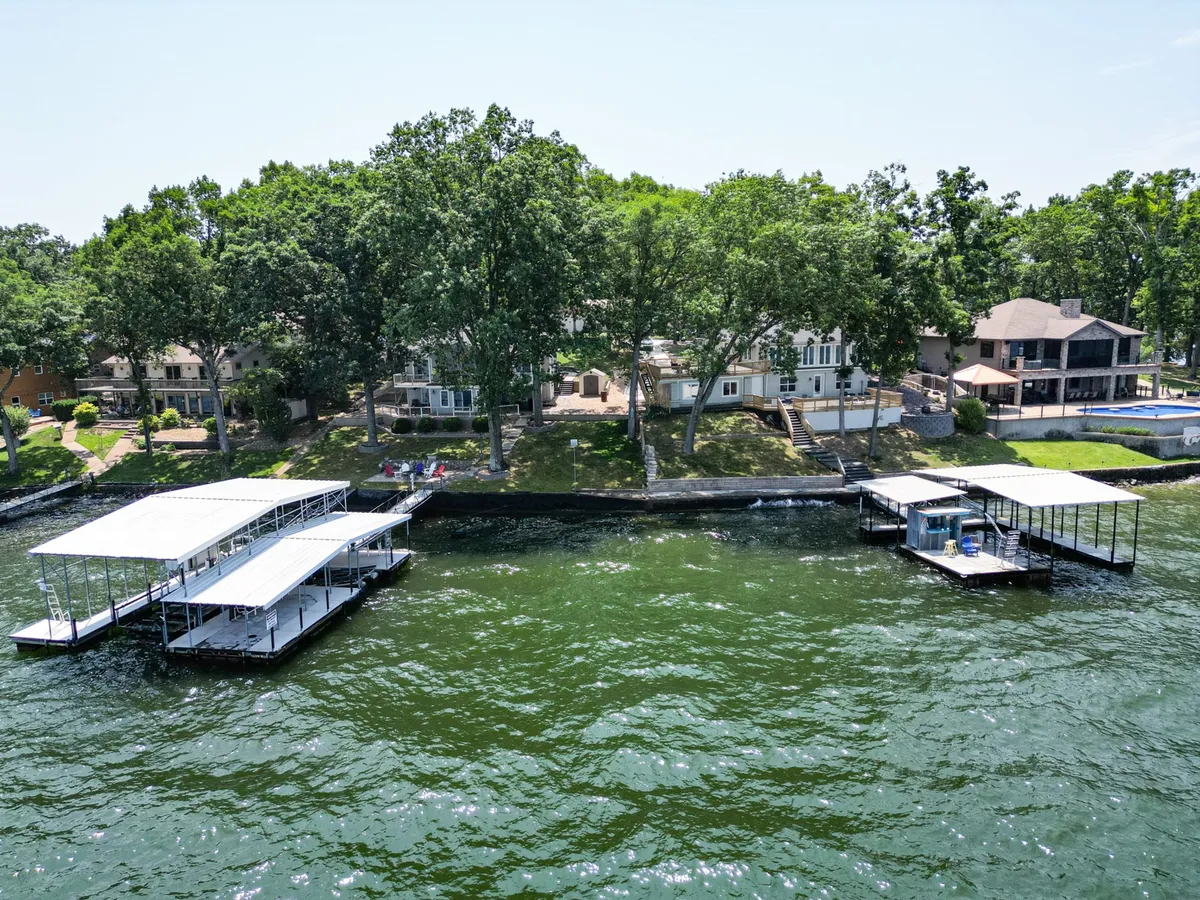A tranquil lakeside scene featuring boathouses nestled among lush green trees. The image captures the essence of lake living, with opportunities for boating, fishing, swimming, and family gatherings right at your doorstep.